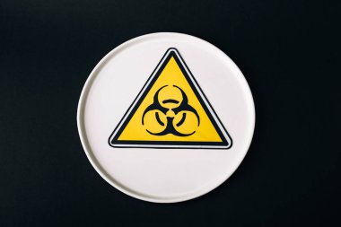 Top view of plate with biohazard sign isolated on black clipart