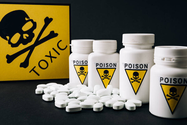 Jars with poison symbol by toxic sign and pills isolated on black