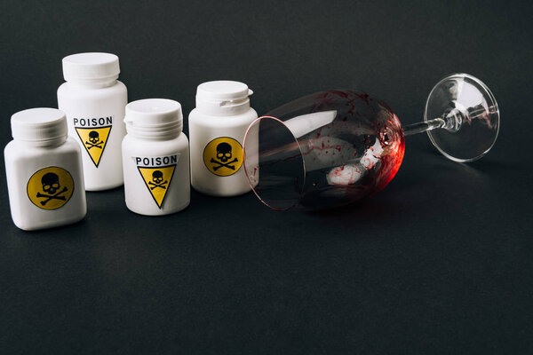 Бокал вина с кровью и банки с ядом знак изолирован на черном
