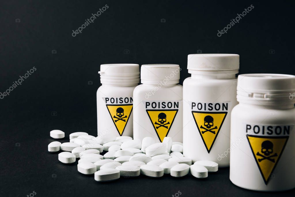 Bottles with poison sign and pills isolated on black