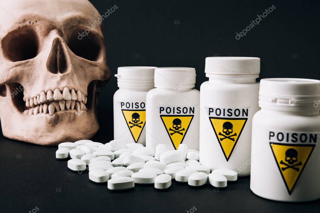 Jars with poison sign by pills and skull isolated on black