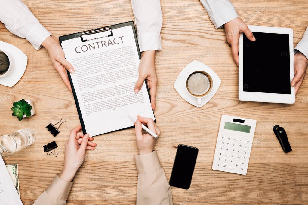 Top view of business partners sign contract with coffee and calculator on table