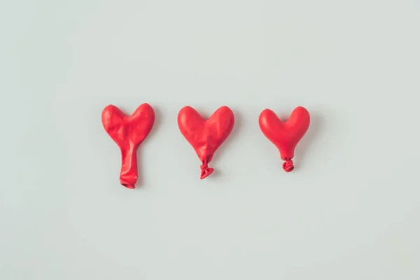 Top view of three deflated heart shaped balloons isolated on white, valentines day concept — Stock Photo
