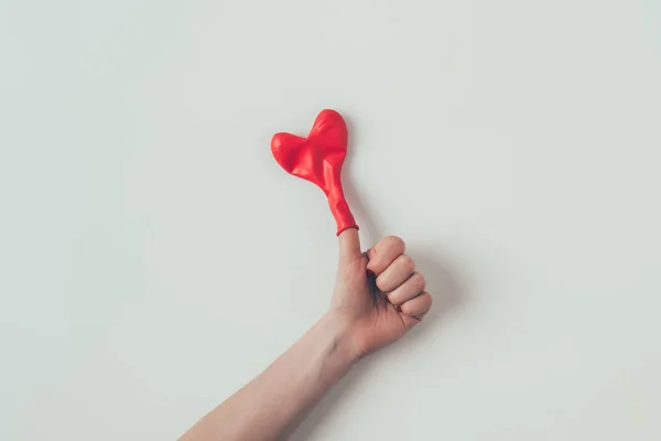 Cropped image of woman showing thumb up with heart shaped balloon on finger on white, valentines day concept — Stock Photo