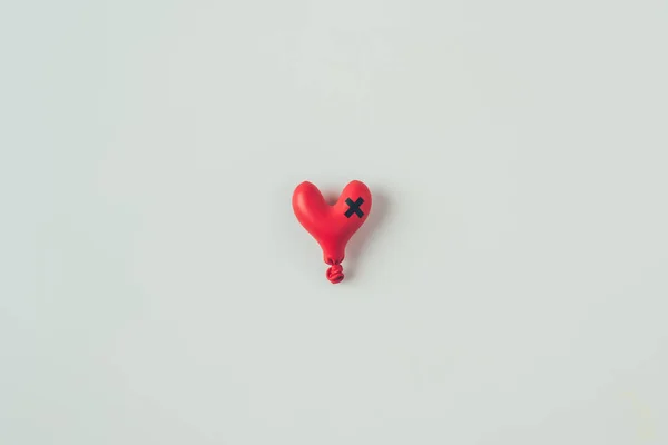 Vue de dessus du ballon dégonflé en forme de coeur avec bande isolante croix isolée sur blanc, concept de Saint-Valentin — Photo de stock