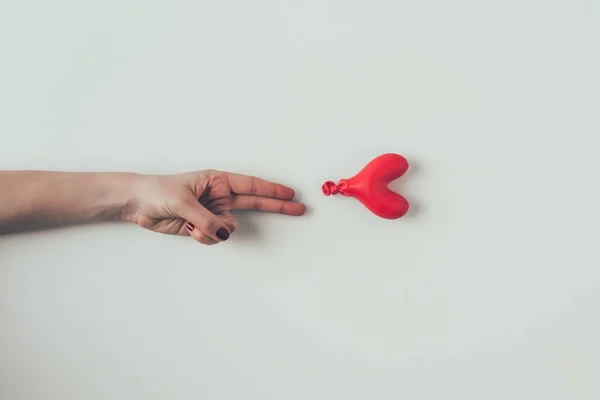 Cropped image of woman reaching out deflated balloon with two fingers on white, valentines day concept — Stock Photo