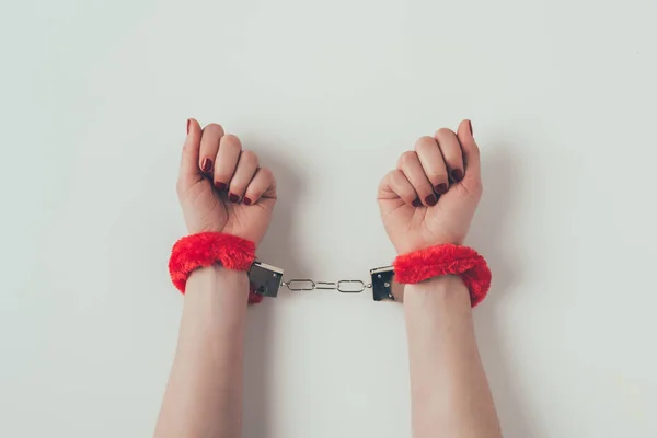 Image recadrée des mains de la femme en rouge menottes moelleuses sur blanc, concept de la Saint-Valentin — Photo de stock