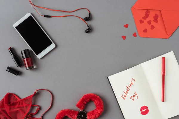 Top view of smartphone, notebook with words valentines day on gray surface — Stock Photo