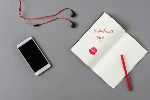 Vista superior del teléfono inteligente y portátil con palabras día de San Valentín en la superficie gris - foto de stock