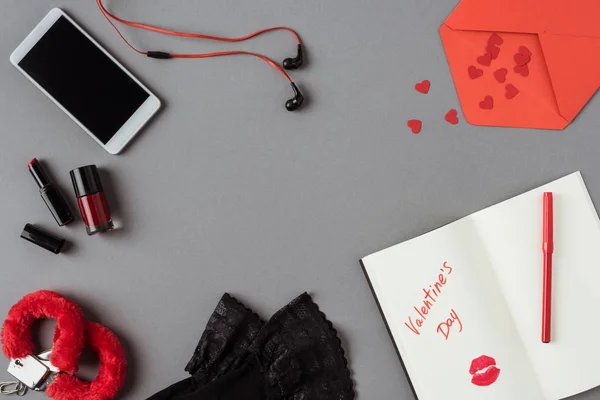 Vista dall'alto di smartphone, notebook con parole giorno di San Valentino su superficie grigia — Foto stock