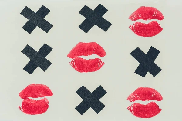 Vista superior de tic-tac-toe con cruces negras y labios estampados aislados en blanco, concepto de día de San Valentín - foto de stock