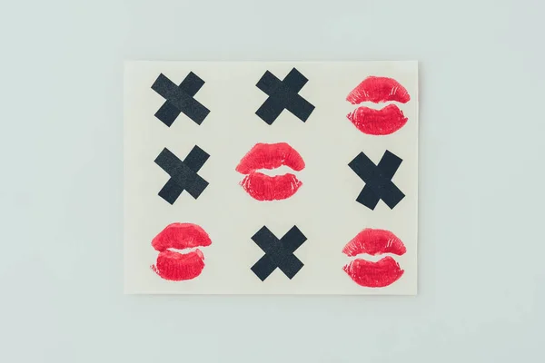 Верхний вид крестики-нолики с черными крестами и отпечатками губ изолированы на белом, валентинки день концепции — стоковое фото