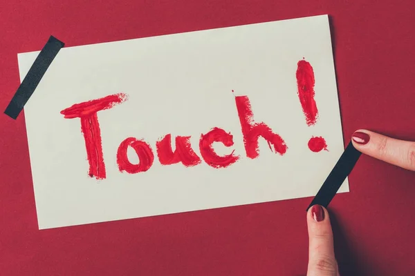 Cropped image of woman putting insulating tape on note with word touch, valentines day concept — Stock Photo