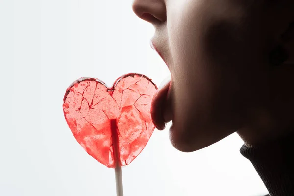 Abgeschnittenes Bild einer Frau, die herzförmigen Lutscher leckt, isoliert auf weißem, Valentinstag-Konzept — Stockfoto