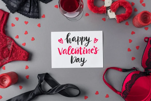 Vue du dessus de feuille blanche de papier avec des mots joyeuse Saint Valentin entre sous-vêtements et verre de vin — Photo de stock