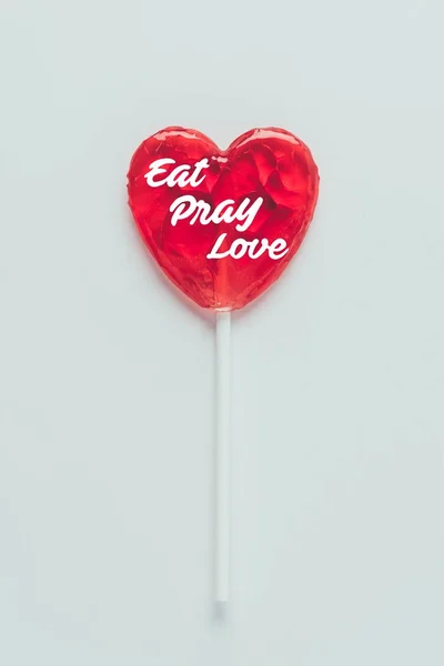 Top view of heart shaped lollipop with words eat pray love isolated on white — Stock Photo