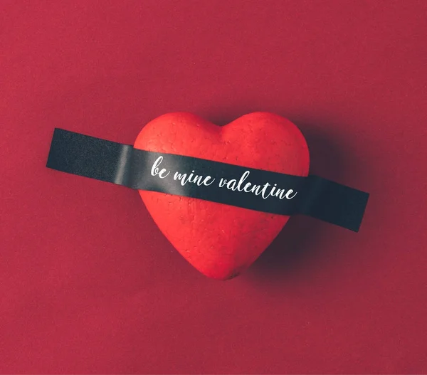 Top view of red heart under insulating tape with words be mine valentine on red — Stock Photo