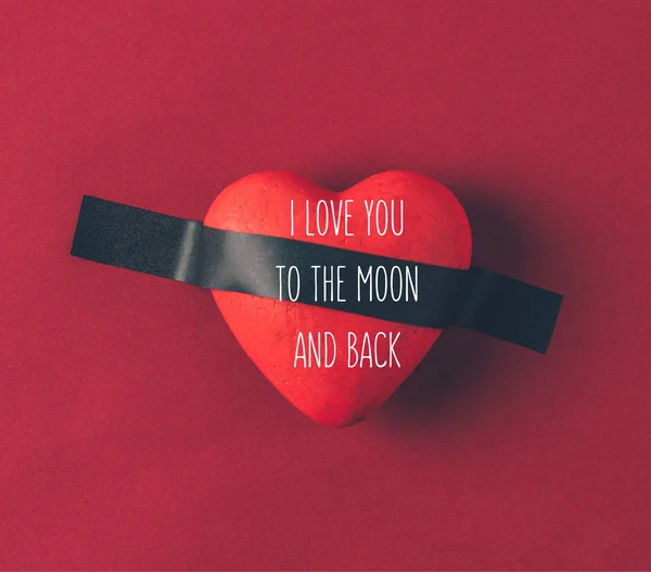 Vista superior del corazón rojo bajo cinta aislante con palabras te amo a la luna y de vuelta en rojo - foto de stock
