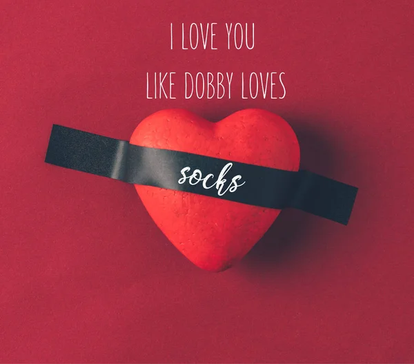 Draufsicht auf rotes Herz unter Isolierband mit den Worten I love you like dobby loves socks on red — Stockfoto