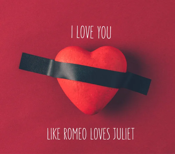 Vista superior del corazón rojo bajo cinta aislante con palabras te amo como romeo le gusta juliet en rojo - foto de stock