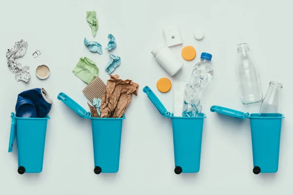 Vista superior de contenedores de basura y basura surtida aislada en gris, concepto de reciclaje - foto de stock