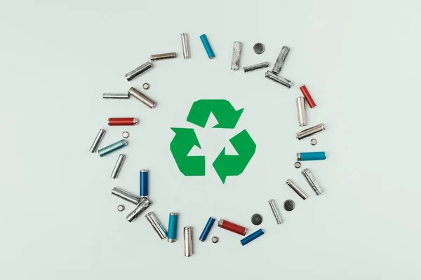 Vista dall'alto del segno di riciclaggio e vari tipi di batterie in cerchio isolato su grigio — Foto stock