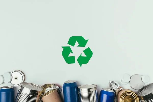 Flat lay com diferentes latas e sinal de reciclagem isolado em cinza — Fotografia de Stock