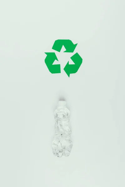 Vista superior do sinal de reciclagem e garrafa de plástico isolado em cinza — Fotografia de Stock