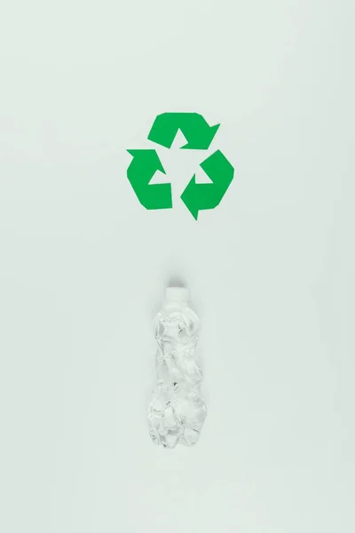 Vue du dessus du panneau de recyclage et bouteille en plastique isolé sur gris — Photo de stock