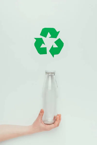 Visão parcial do homem segurando garrafa de vidro com sinal de reciclagem isolado no cinza — Fotografia de Stock