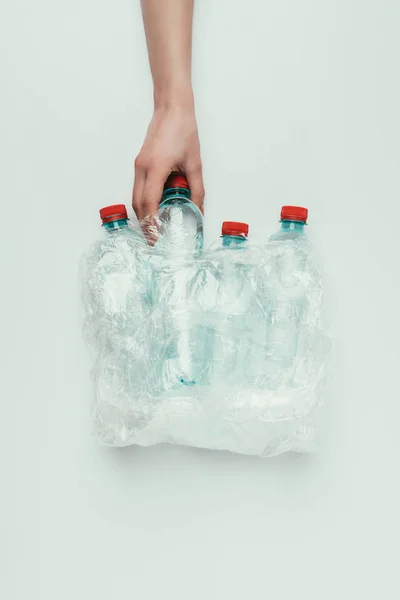 Vista parziale della donna che prende bottiglia di plastica dal sacchetto di plastica isolato su grigio — Foto stock