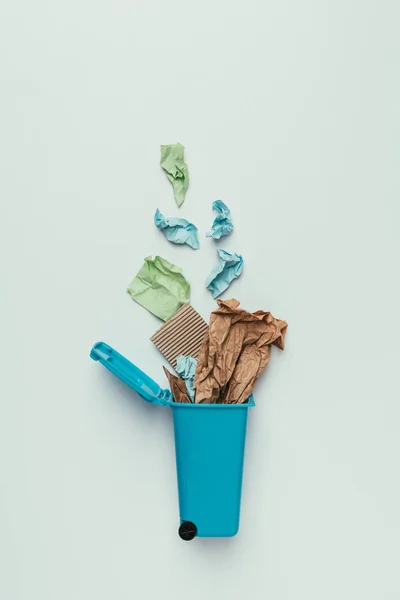 Vista superior de la papelera con basura de papel aislada en gris, concepto de reciclaje - foto de stock