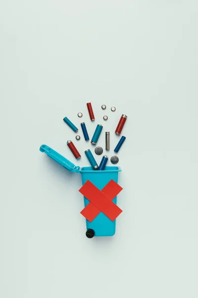 Top view of trash bin with red cross and batteries isolated on grey, recycling concept — Stock Photo