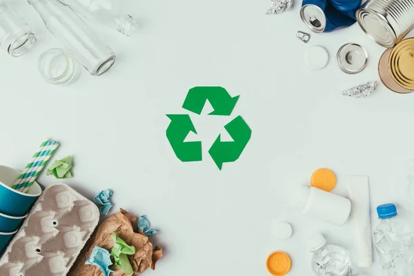 Flache Liege mit arrangierten verschiedenen Müllarten und Recyclingschild isoliert auf grau — Stockfoto