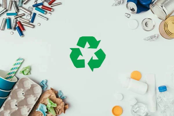 Flache Liege mit arrangierten verschiedenen Müllarten und Recyclingschild isoliert auf grau — Stockfoto