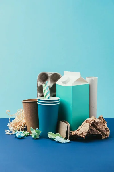 Vue rapprochée des déchets jetables en carton et papier disposés sur fond bleu — Photo de stock