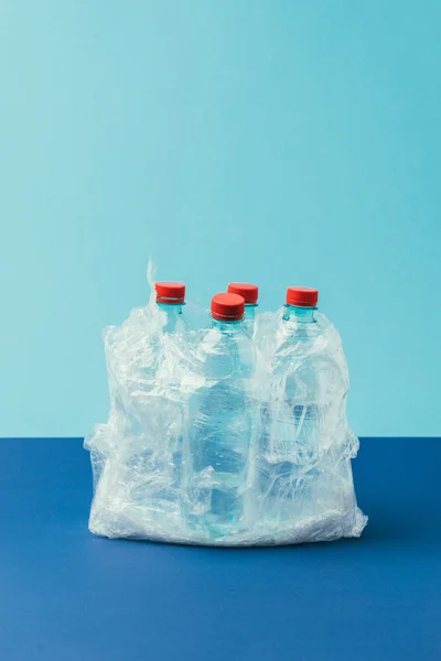 Vista de perto de garrafas de plástico em saco de plástico no fundo azul, conceito de reciclagem — Fotografia de Stock