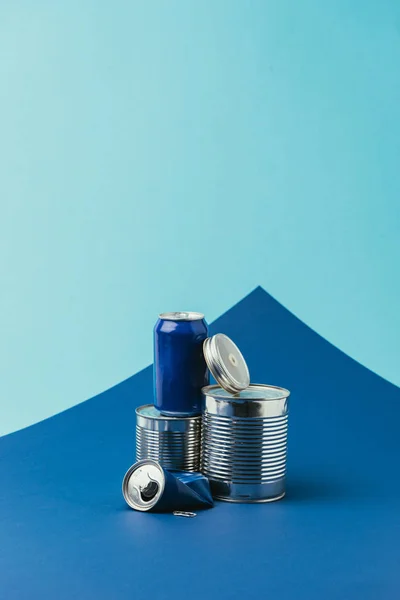 Vista de perto de latas de metal dispostas no fundo azul, conceito de reciclagem — Fotografia de Stock