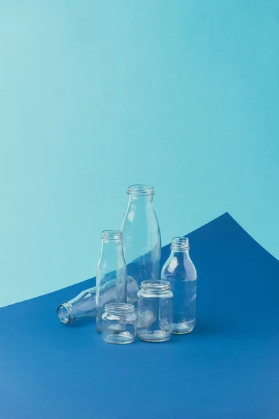 Close up view of various glass bottles and jars on blue background, recycle concept — Stock Photo