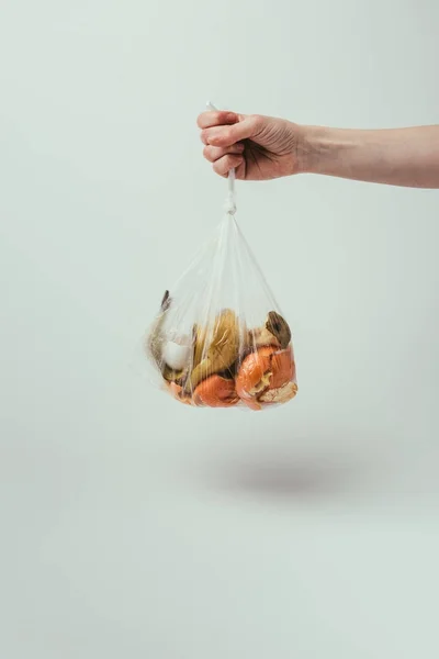 Cropped shot of woman holding plastic bag with trash on grey background — Stock Photo