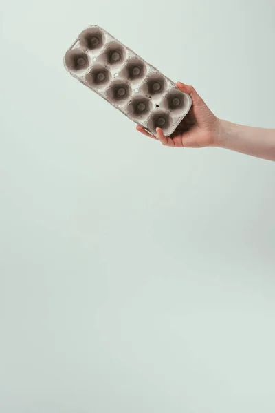 Cropped shot of woman holding empty carton egg box isolated on grey — Stock Photo