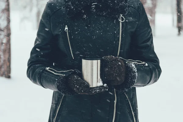 Частковий вид жінки, що тримає термоап з гарячим напоєм в зимовий день — стокове фото