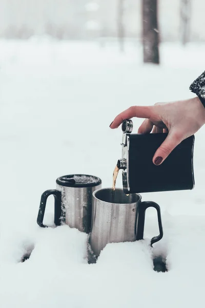 Partial view of woman pouring coffee into cups in snow in winter — Stock Photo