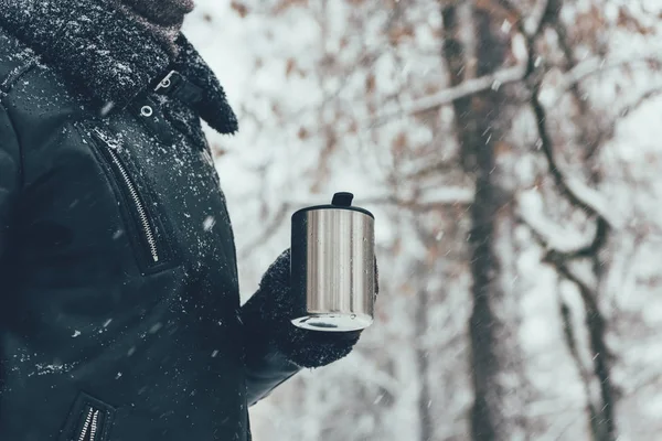 Vue partielle de la femme tenant thermotasse avec boisson chaude le jour d'hiver — Photo de stock
