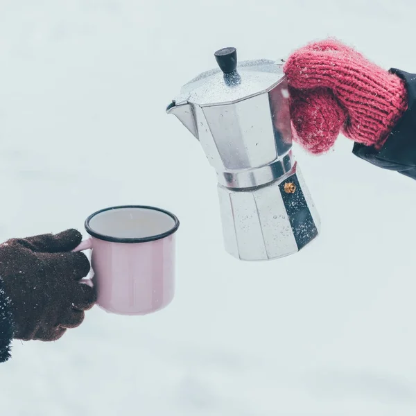 Cropped shot of couple holding cup and coffee maker in hands on winter day — Stock Photo