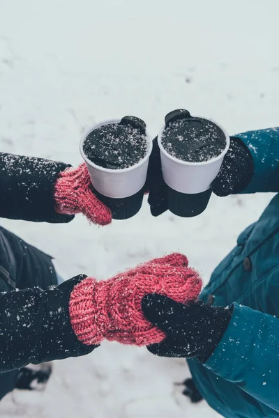 Teilansicht eines Pärchens mit heißen Getränken, das sich im Winter auf der Straße an den Händen hält — Stockfoto