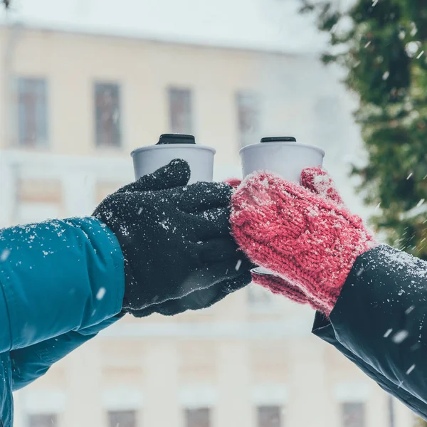 Cropped shot of couple holding thermocups with hot drinks on street in winter — Stock Photo