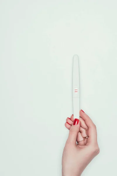 Partial view of woman holding pregnancy test with two lines in hand isolated on white — Stock Photo