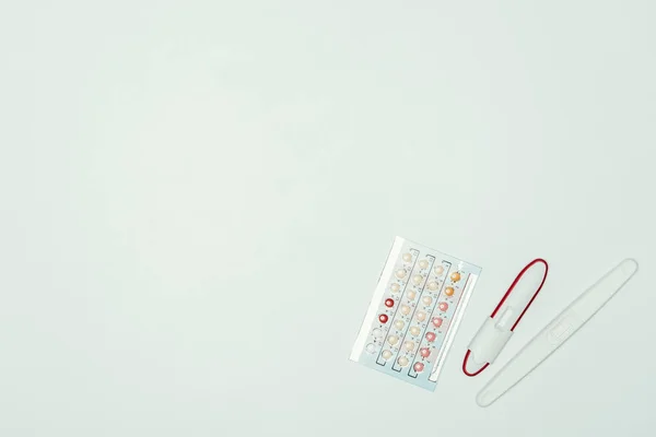 Vue du dessus des pilules contraceptives et test de grossesse isolé sur gris — Photo de stock