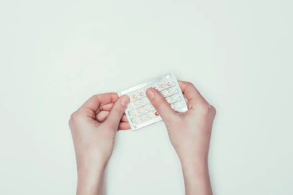 Inyección recortada de mujer sosteniendo píldoras anticonceptivas en las manos aisladas en gris - foto de stock